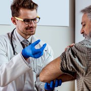 Doctor injecting senior patient in clinic. Medical exam. Vaccination..